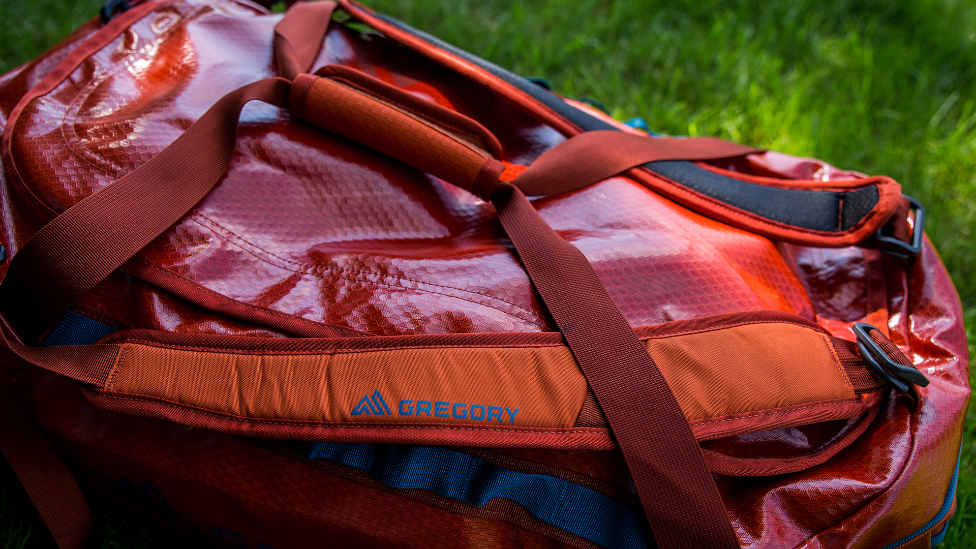 A close-up of a Gregory Alpaca 60 on a patch of grass, with the handles closed over the top.