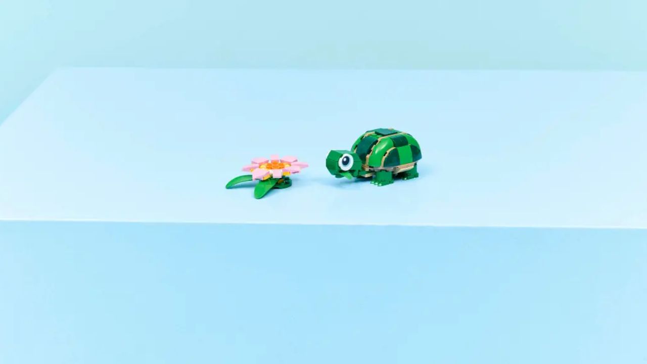 A Lego turtle and flower on a blue surface