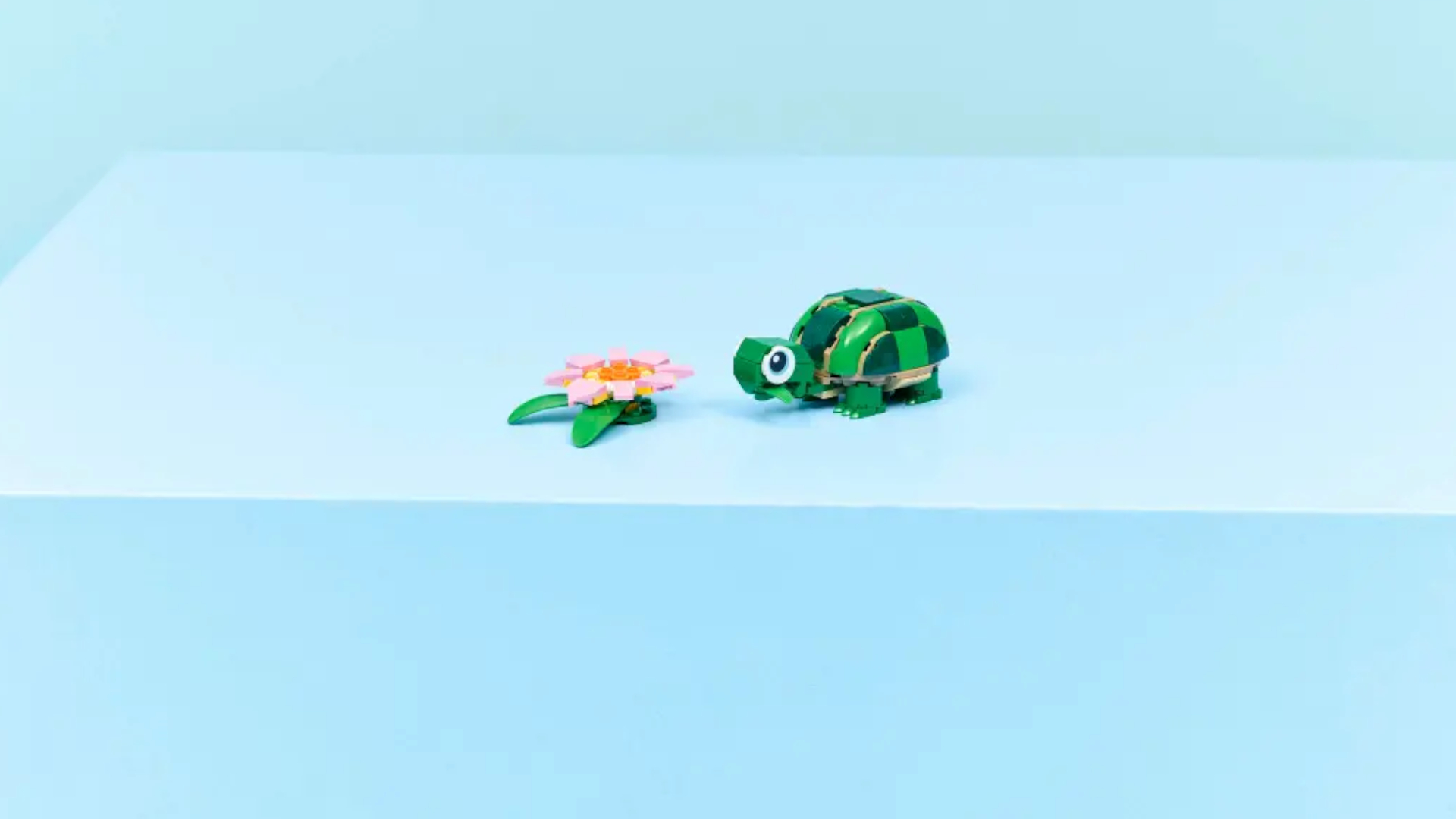 A Lego turtle and flower on a blue surface