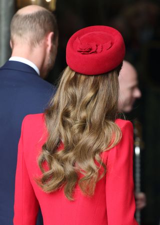 The back of Kate Middleton's head wearing a red hat and red coat