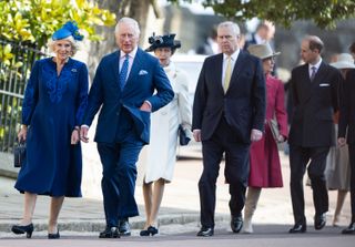 King Charles and Queen Camilla wearing blue outfits walking in front of Princess Anne and Prince Andrew, Duchess Sophie and Prince Edward on a sunny day