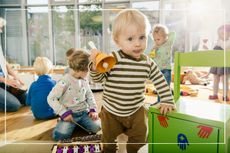 Toddler playing with toys and other children at nursery