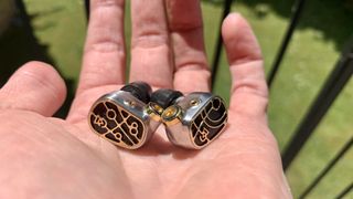 Campfire Audio Solaris Stellar Horizon held in the palm of a hand on a sunny day, showing a closeup of the ornate driver housings
