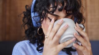 Young woman wearing headphones drinking coffee