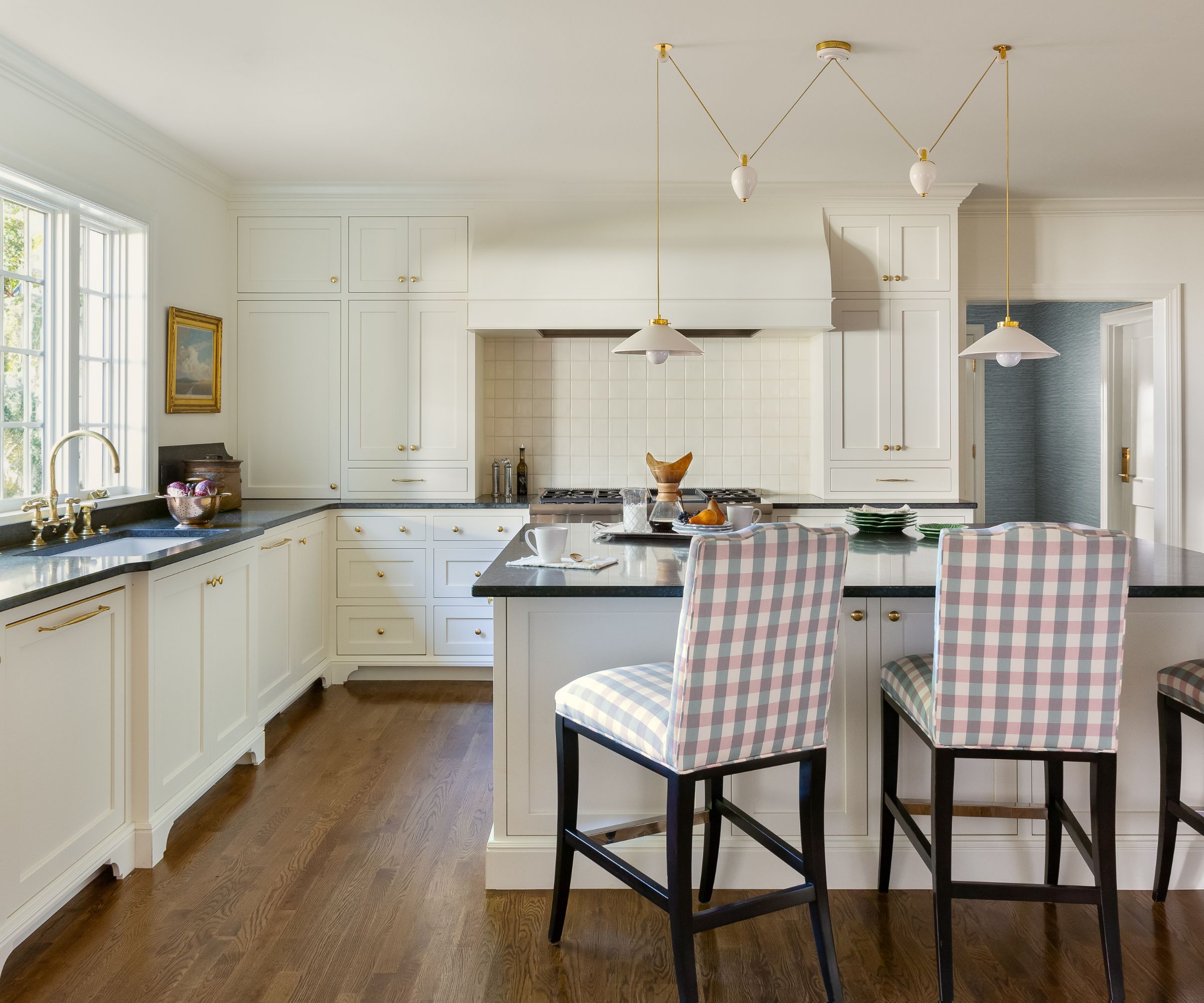 traditional kitchen with off-white cabinets, wood floors, gingham bar chairs