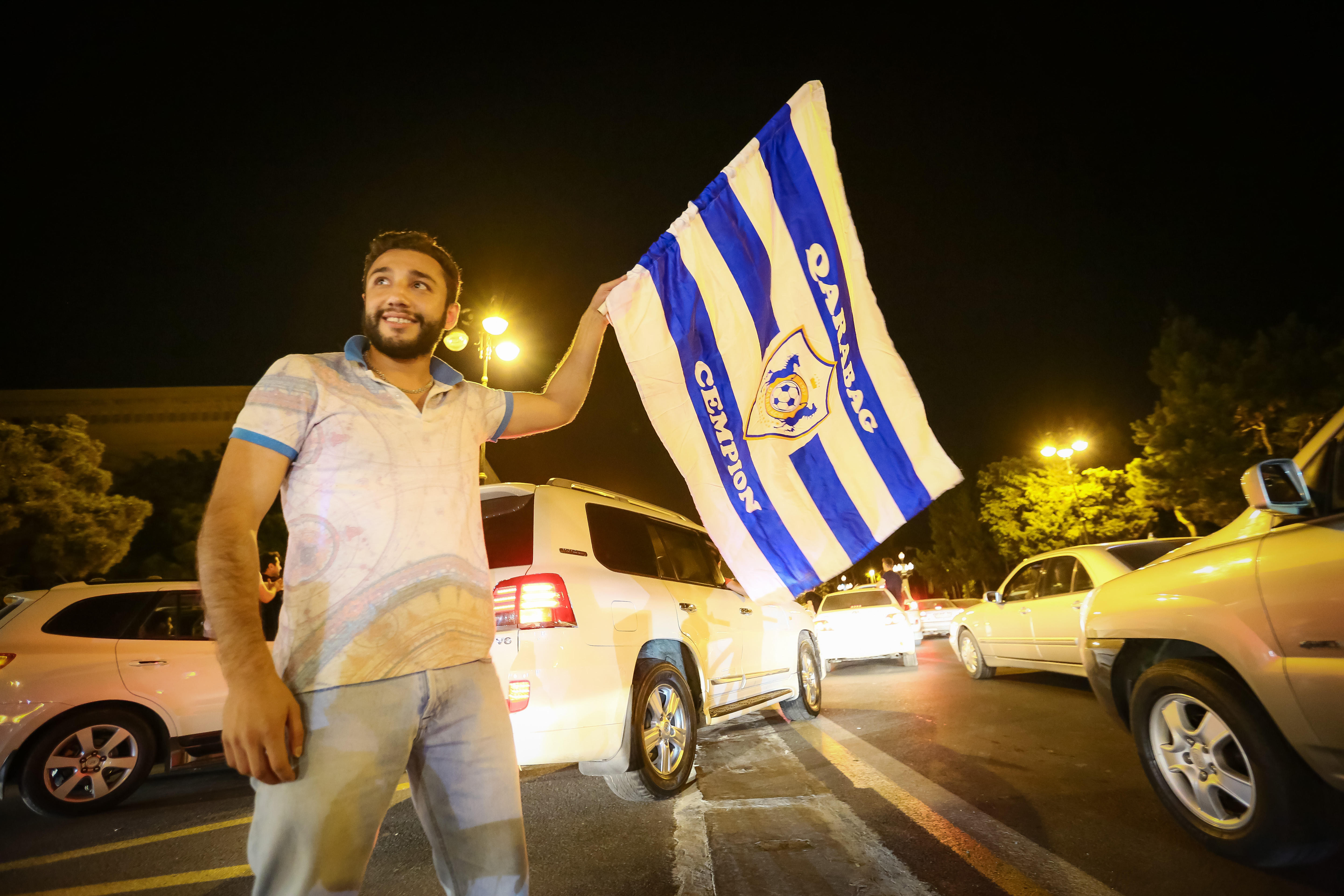 A Qarabag fan celebrates with a flag bearing the club's crest, 2017