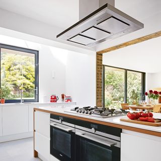 white kitchen island with integrated double over and extractor fan above