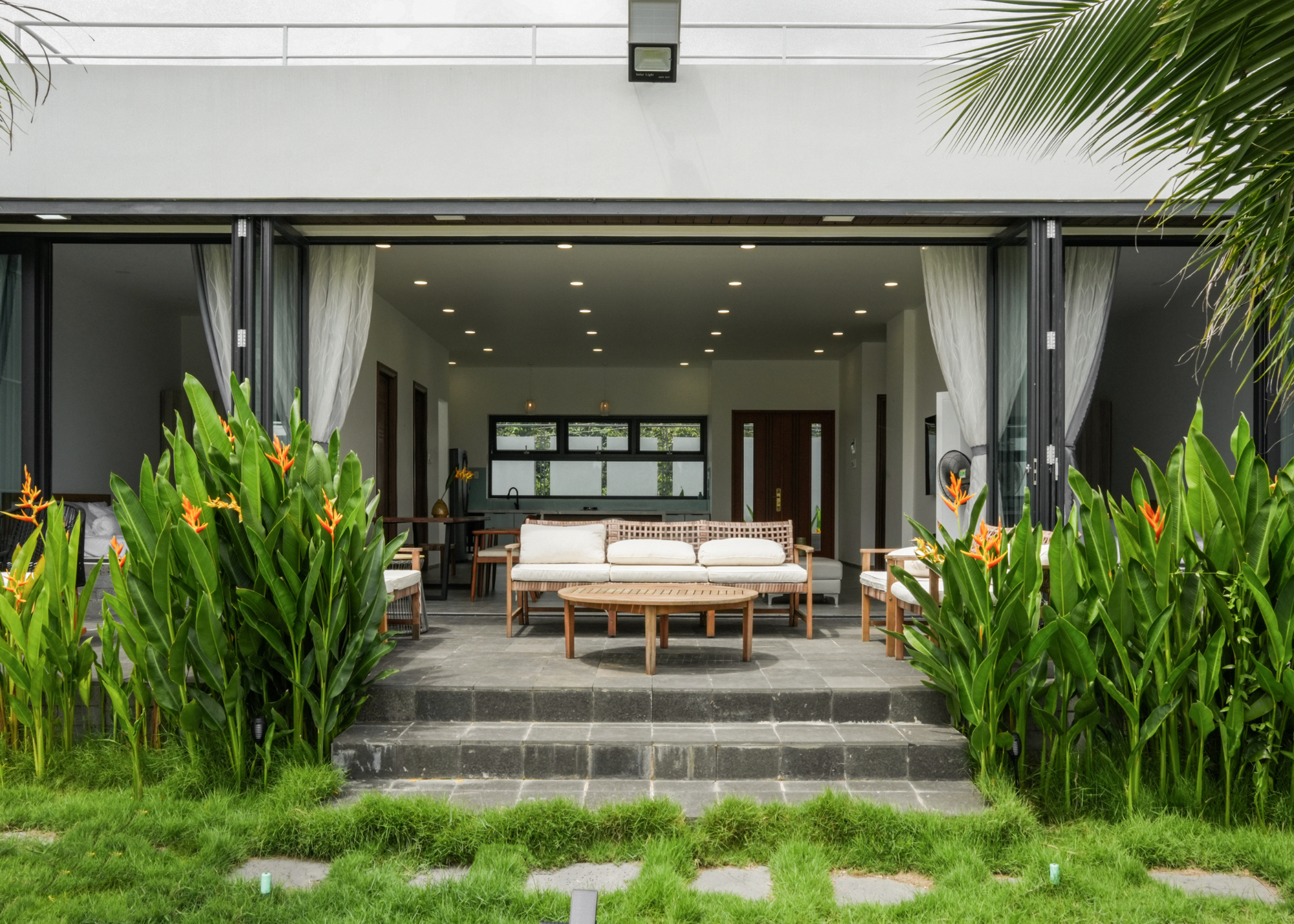 tropical patio leading on from living room, patio is paved and has a seating area