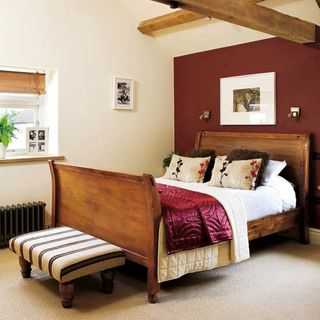 bedroom with wooden ceiling beams and ruby coloured walls