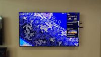 Wall-mounted TCL C7L with vibrant demo content on screen