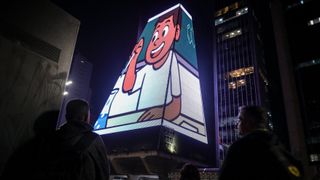 The SESI Digital Gallery on the FIESP building in S&atilde;o Paulo lit up by 120,000 LED dots showing cartoon men and women. 