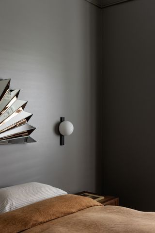 A bedroom with dark grey walls and brown bedding