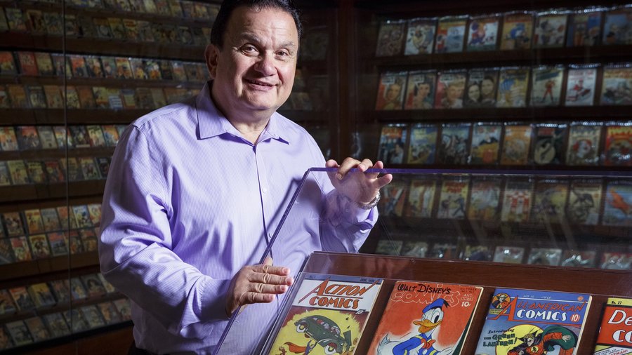 CEO and founder of Diamond Comic Distributors, Steve Geppi beside a shelf of comic books