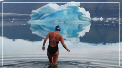 Kate Steels with back to camera entering ice cold water with large iceberg ahead, showing the sport of ice swimming