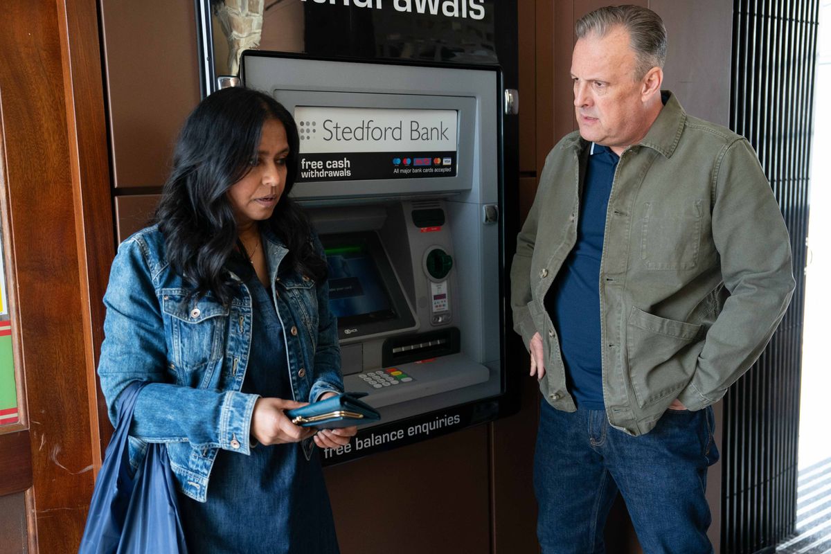 A concerned Harvey Monroe looks at Maya Houssain next to a cashpoint. 