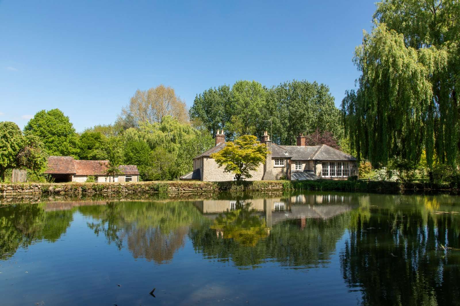 Fox Mill Farm viewed from the water, with overhanging willows in the foreground