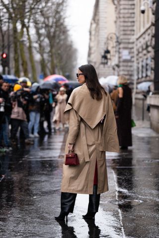 Zina Charkoplia, wears beige trench coat, black pants, burgundy Hermes bag, outside Hermes, during the Womenswear Fall/Winter 2024/2025 as part of Paris Fashion Week on March 02, 2024 in Paris, France.