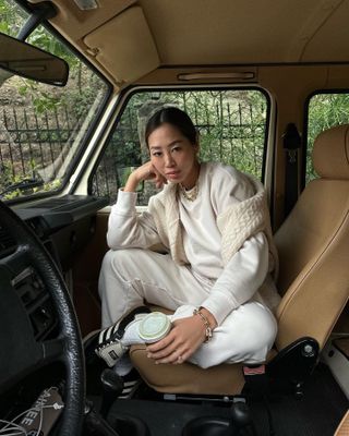 @aimeesong wearing white sweatsuit with cable-knit sweater and black Adidas Sambas.