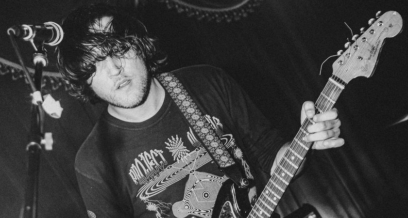A black-and-white action shot of Josh Menashe playing his Fender Jazzmaster live.