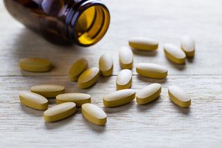 Vitamin C pills spill out of a jar