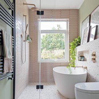 narrow pink and green bathroom with a large contemporary bath, and matching WC, as well as a walk-in shower, black wall-hung radiator and large window