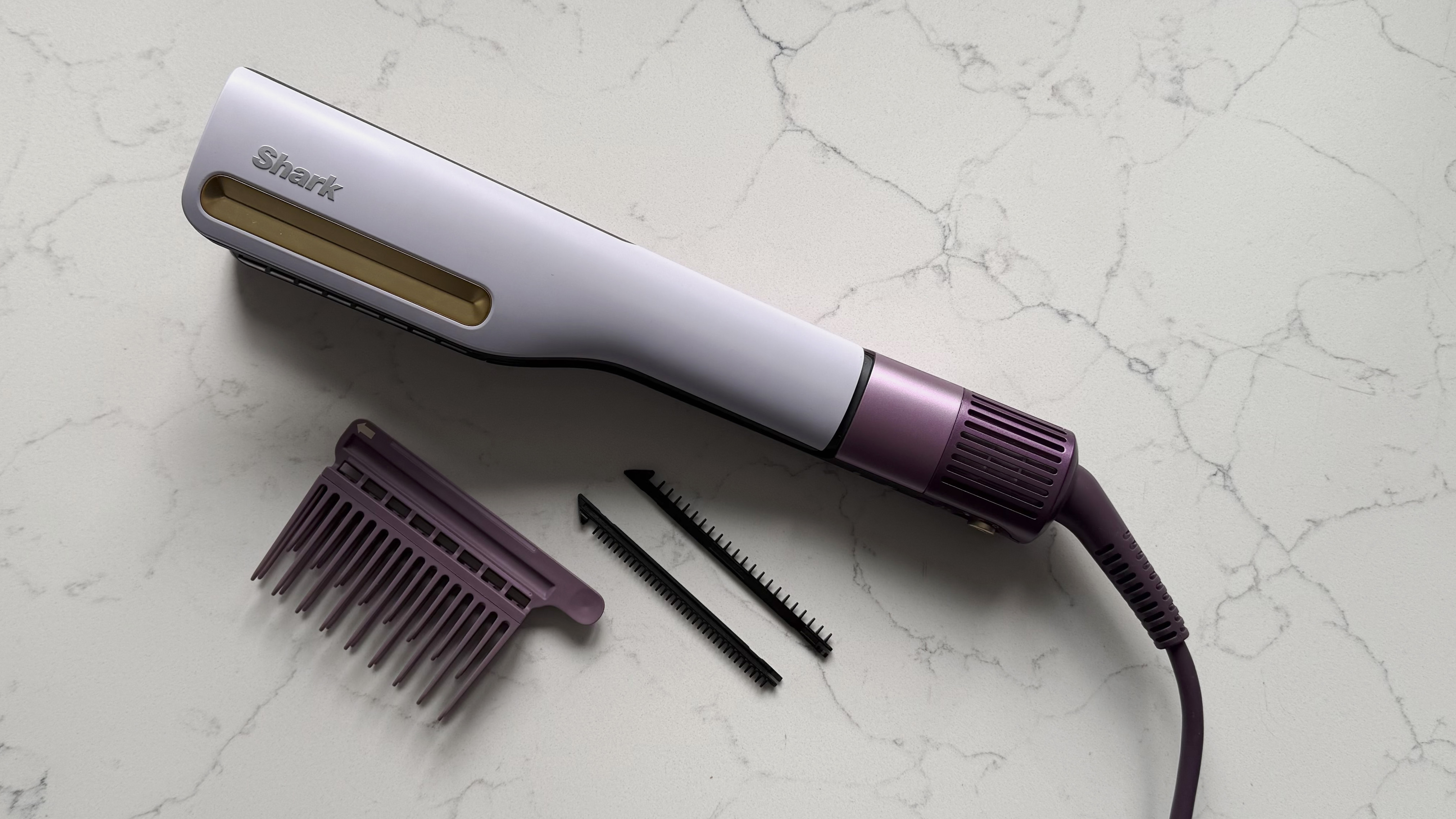 Top-down view of the Shark SilkiPro Straight with all three comb attachments laid out alongside it on a marble surface