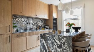 modern wooden kitchen with black and white marble island and splashback