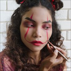 Woman Putting On Evil Clown Makeup for Halloween