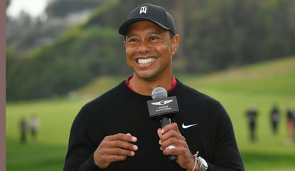 Woods smiles while holding a microphone 