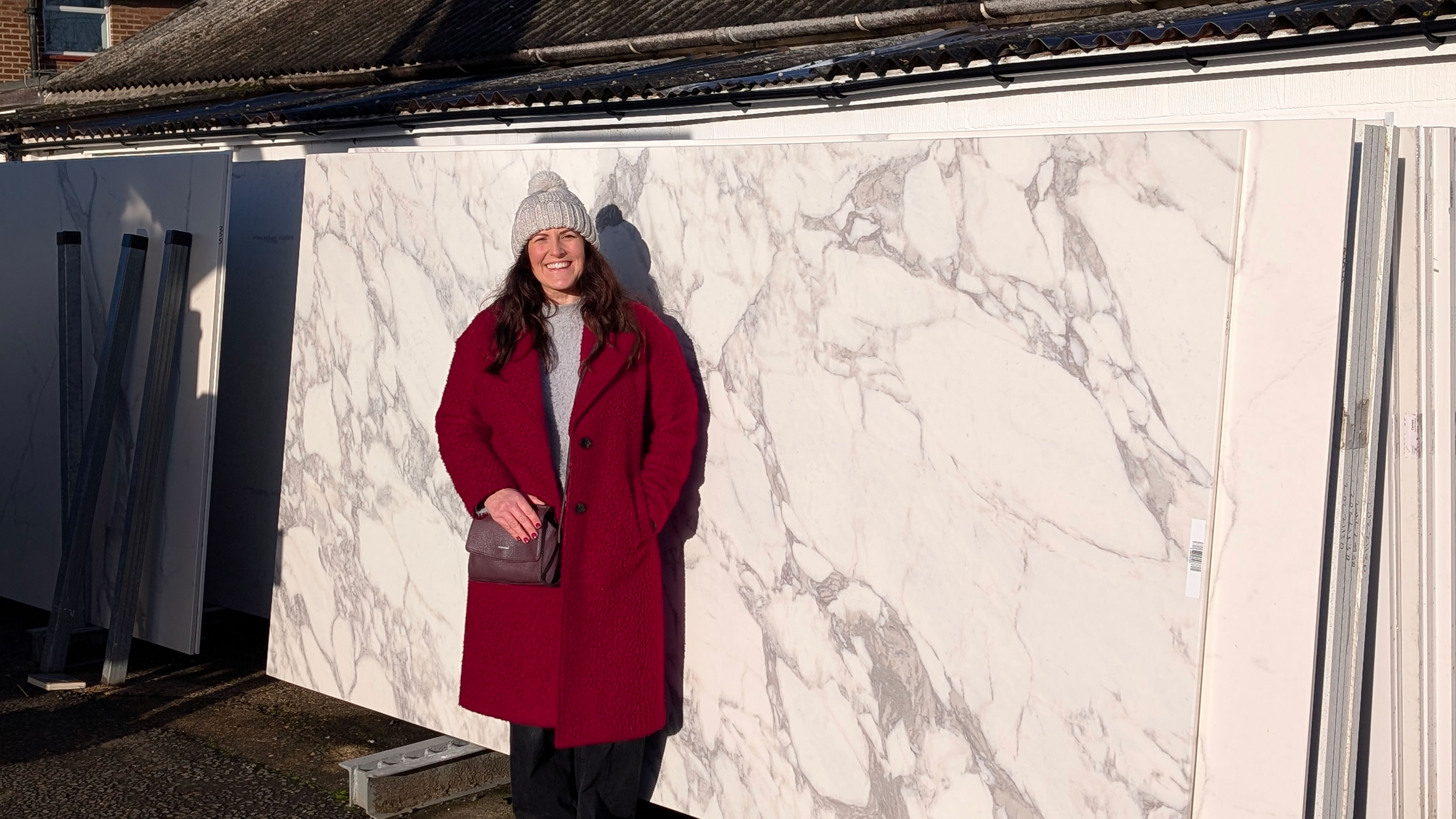 Woman in red coat standing in front of large marble slab