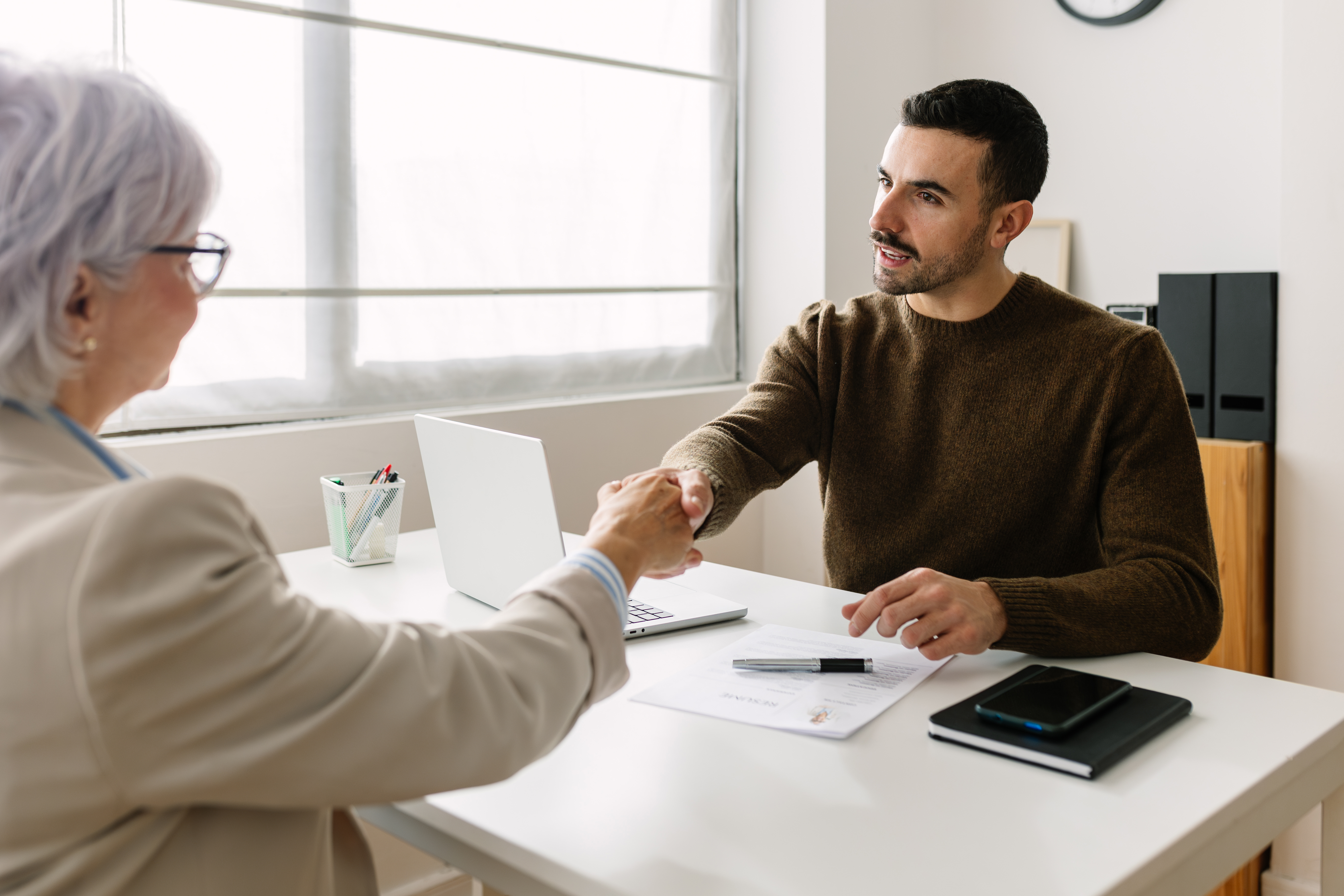 An older worker shakes hands with a recruiter.