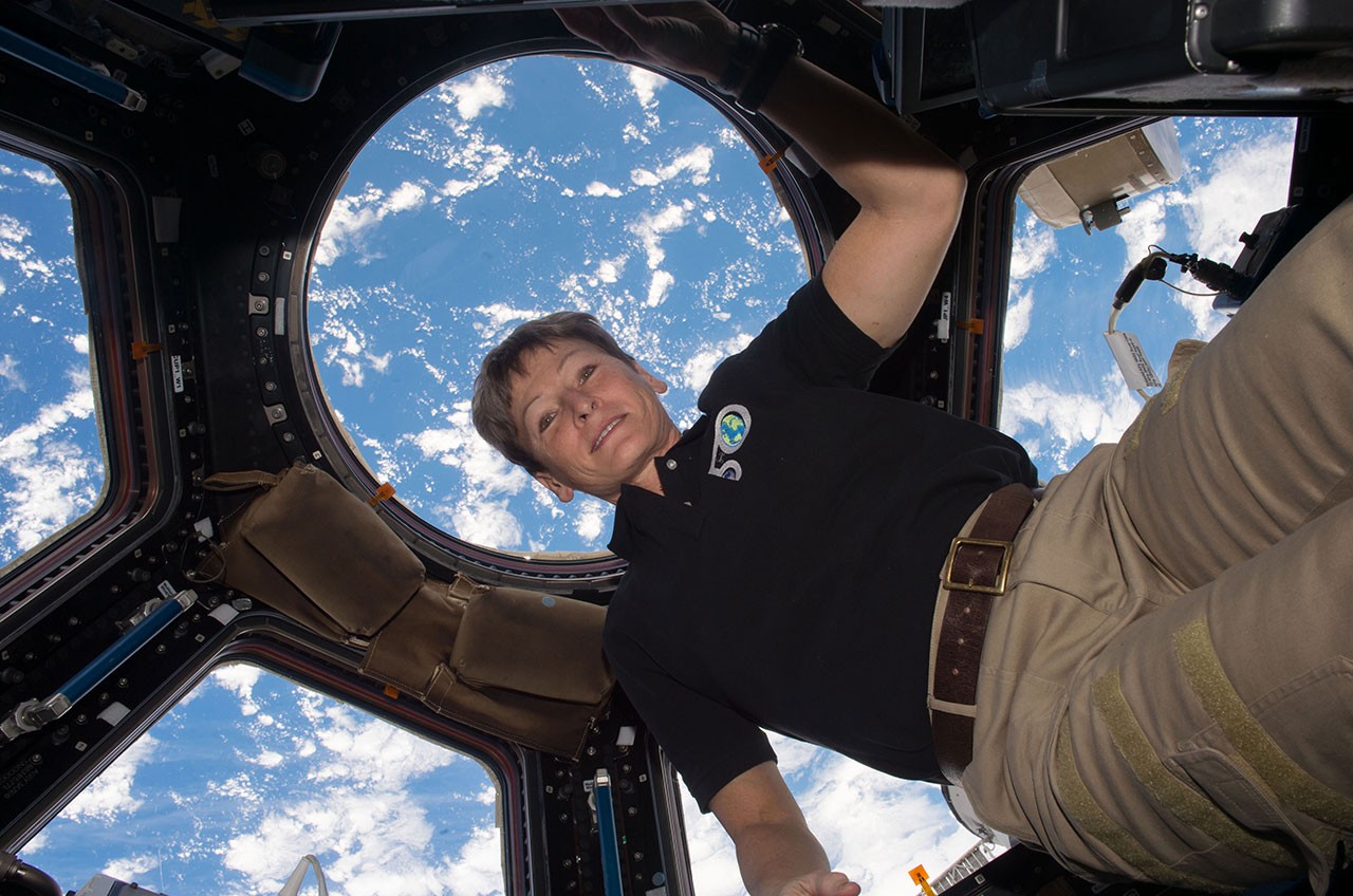 Astronaut Peggy Whitson floats in the cupola on board the International Space Station, backdropped by the Earth below. 