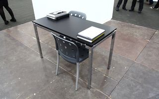 Black desk table with silver legs and black chairs with circle cut-out back support