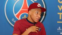 A young Kylian Mbappe wearing a PSG shirt and a Nike cap.