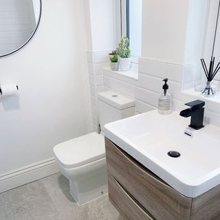 bathroom with white wall and black tap