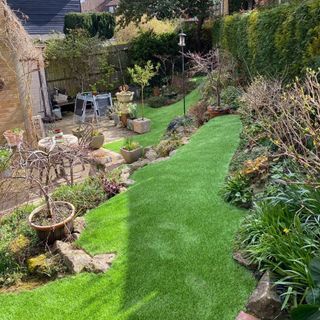 Lawn of fake grass surrounded by plant beds
