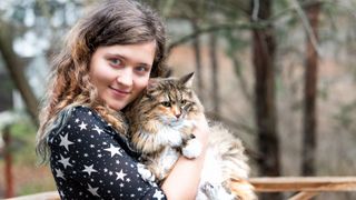 Woman holding Norwegian forest cat outside
