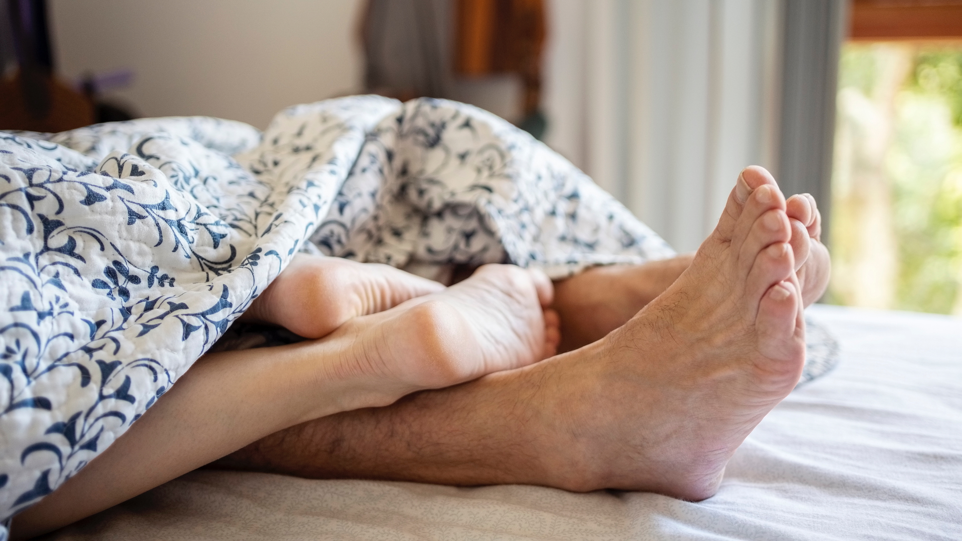 A man and woman's feet in bed