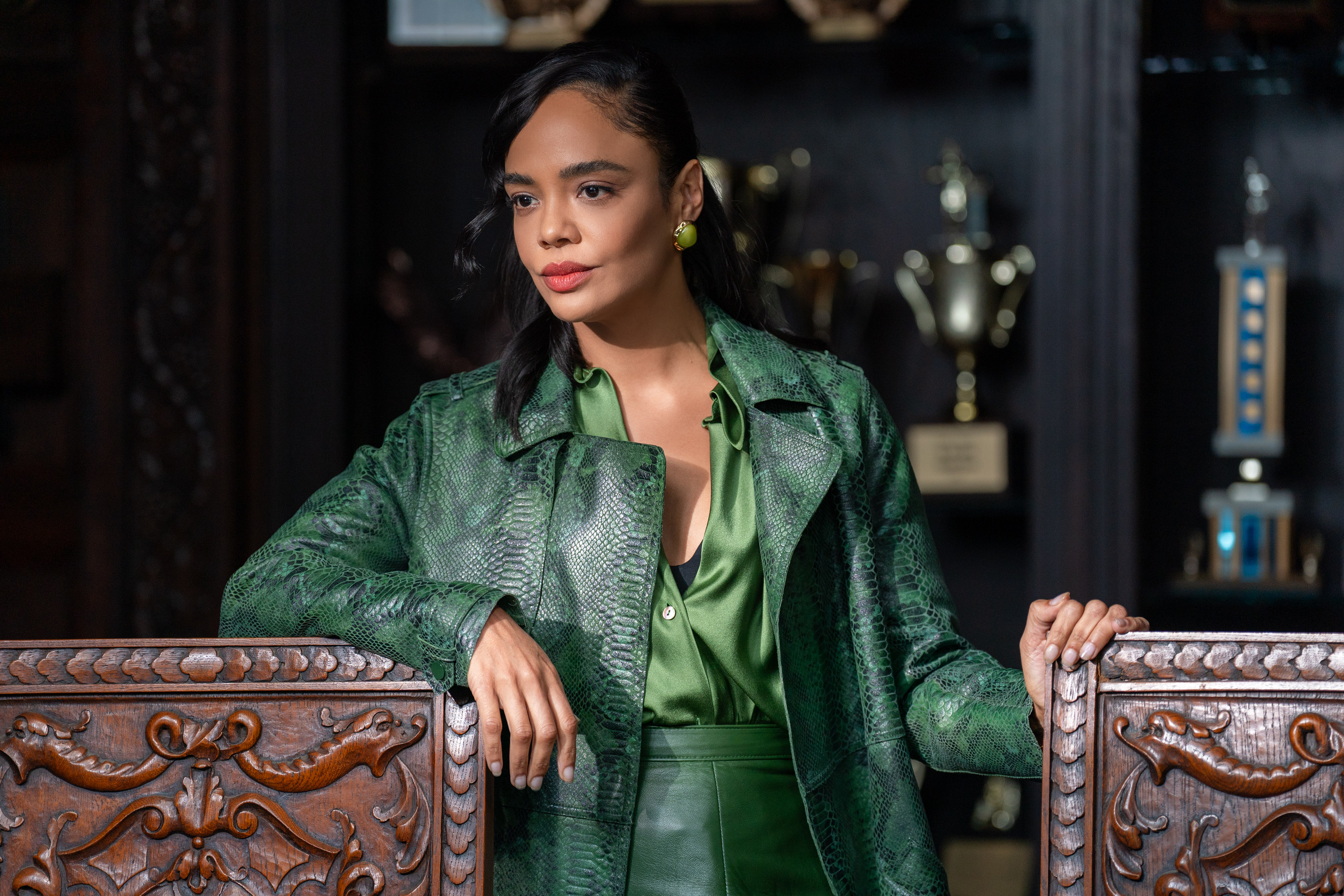 Tessa Thompson as Anna wearing a green snake skin coat and green outfit standing in front of a wall of trophies in Episode #102 of His &amp;amp; Hers