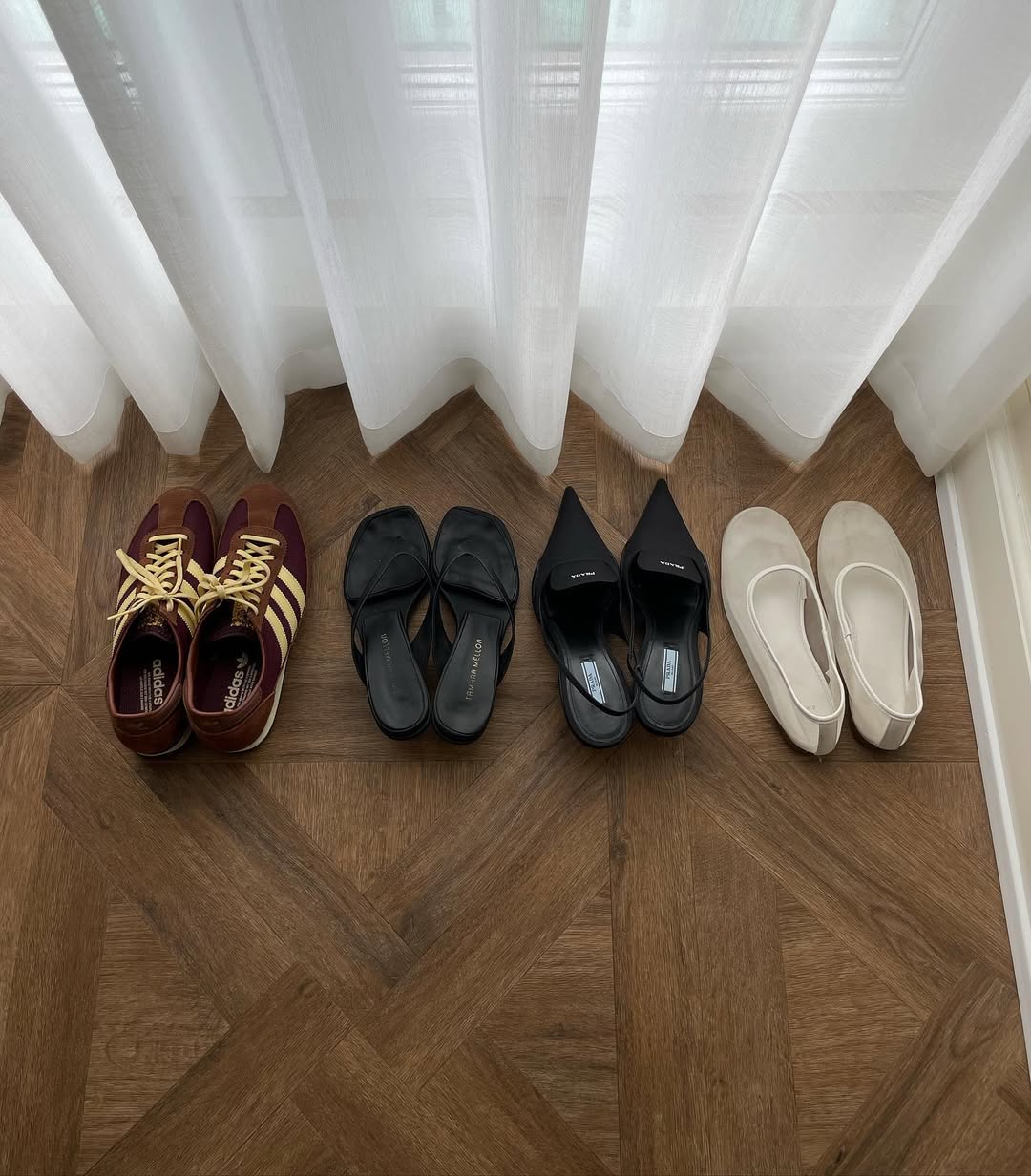 Four pairs of shoes lined up in a hotel room.