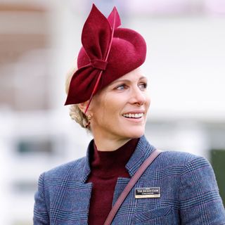 Zara Tindall wearing a gray suit and maroon hat