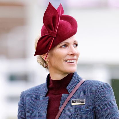 Zara Tindall wearing a gray suit and maroon hat