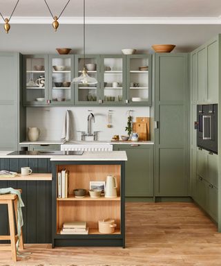 Green kitchen with glass-fronted upper cabinets above the sink