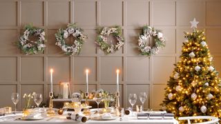Dusky pink dining room with christmas tree and wreaths along one wall as alternative wall decor