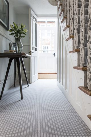 hallway with light colour scheme and small console table and runner carpet by cormar carpets