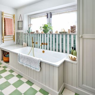 built-in bathtub on top of green and white floor tiles underneath storage shelf and wall tiles