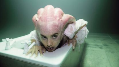 Isamaya Ffrench in prosthetic monster makeup crawling out of bathtub 