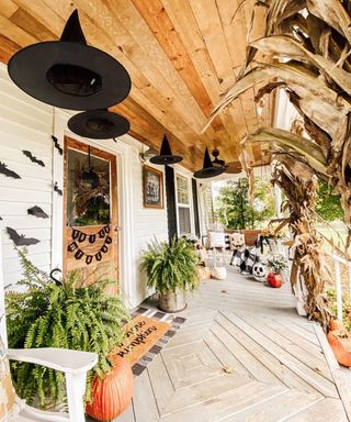 Halloween outdoor decor ideas on porch with floating witches' hats, trick or treat bunting and pumpkins