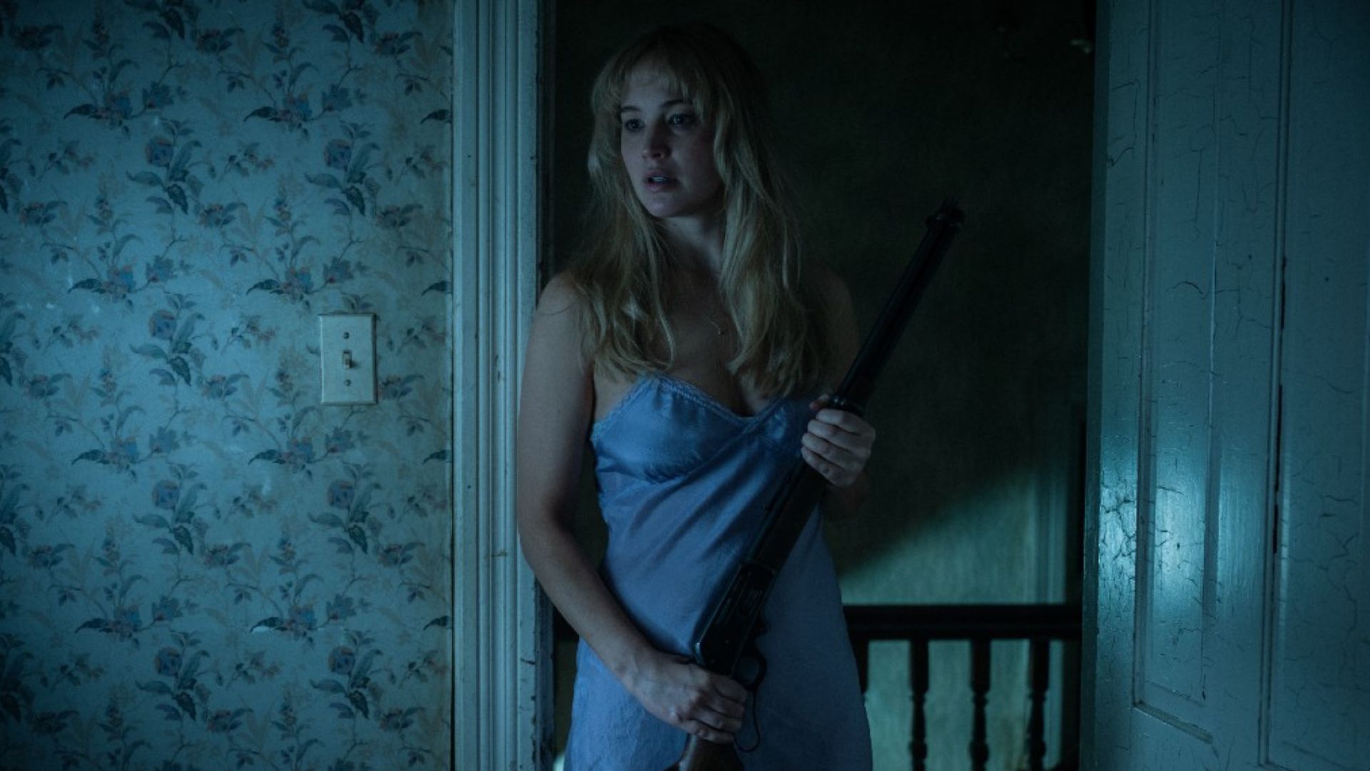Jennifer Lawrence holds a gun in a doorway