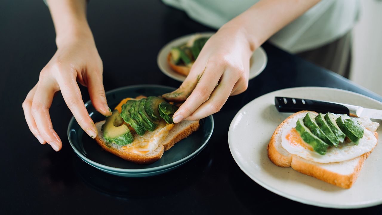 woman preparing avocado on toast with eggs